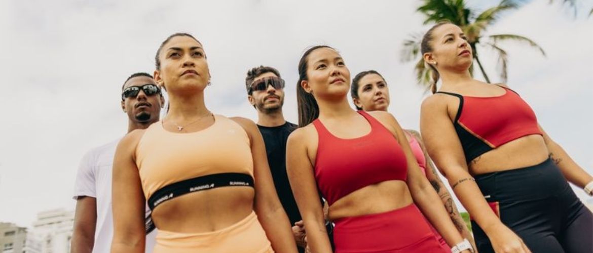 Grupo de pessoas praticando ao ar livre em clima ensolarado, com roupas de compressão para maratona coloridas.