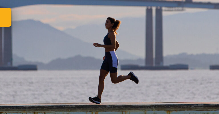 Mulher correndo em frente à Ponte Rio Niterói usando Linha Reflect da Authen | Academia fechada? A corrida ao ar livre pode ser sua salvação
