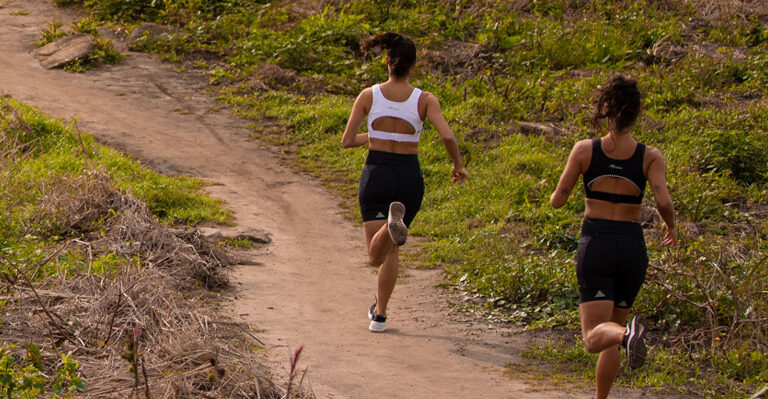 Mulheres correndo juntas em trilha vestindo a Linha GRIT Trail | Como voltar a correr de forma segura (para você e para todos)