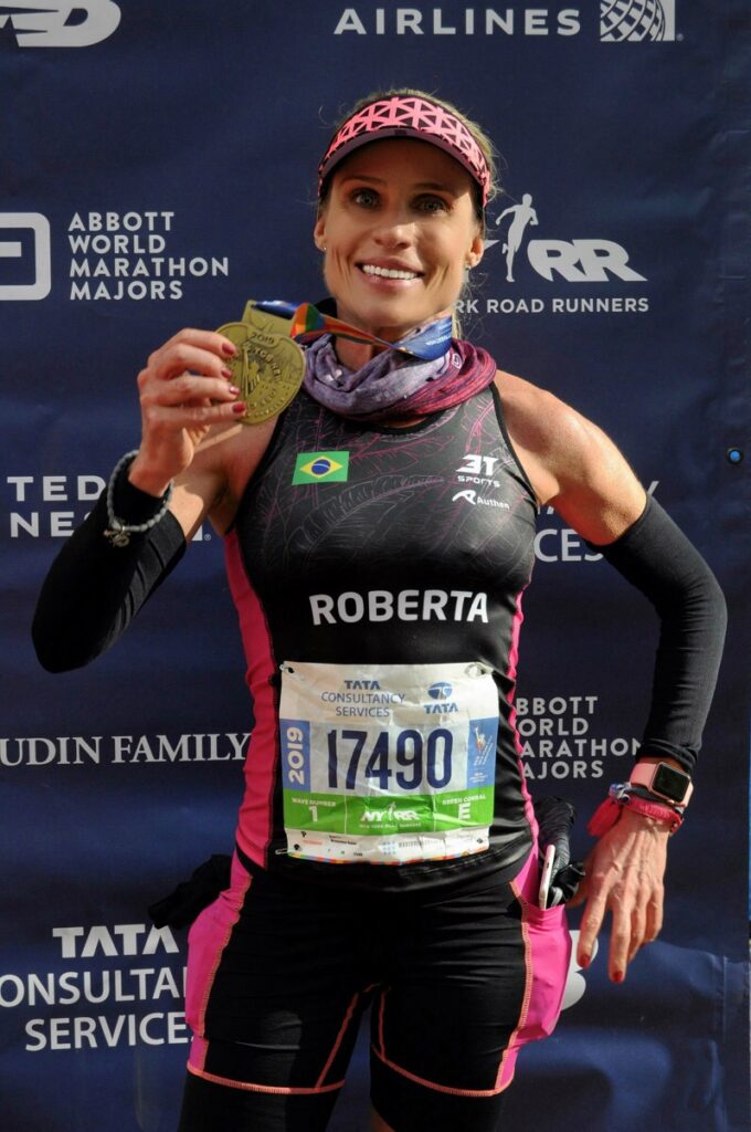 Roberta Weisheimer comemorando sua medalha após completar maratona | Somos corredoras, somos inspiração