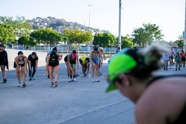 Grupo de pessoas se preparando para voltar a correr em um parque ao ar livre no Brasil, com foco em exercícios de aquecimento e retomada de corrida.